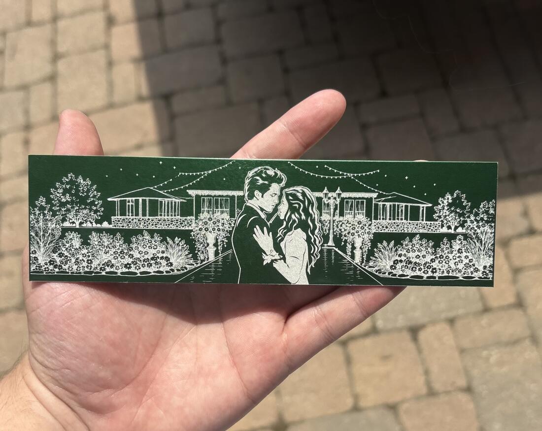 Forest green aluminum bookmark engraved with a couple dancing under string lights in front of a house