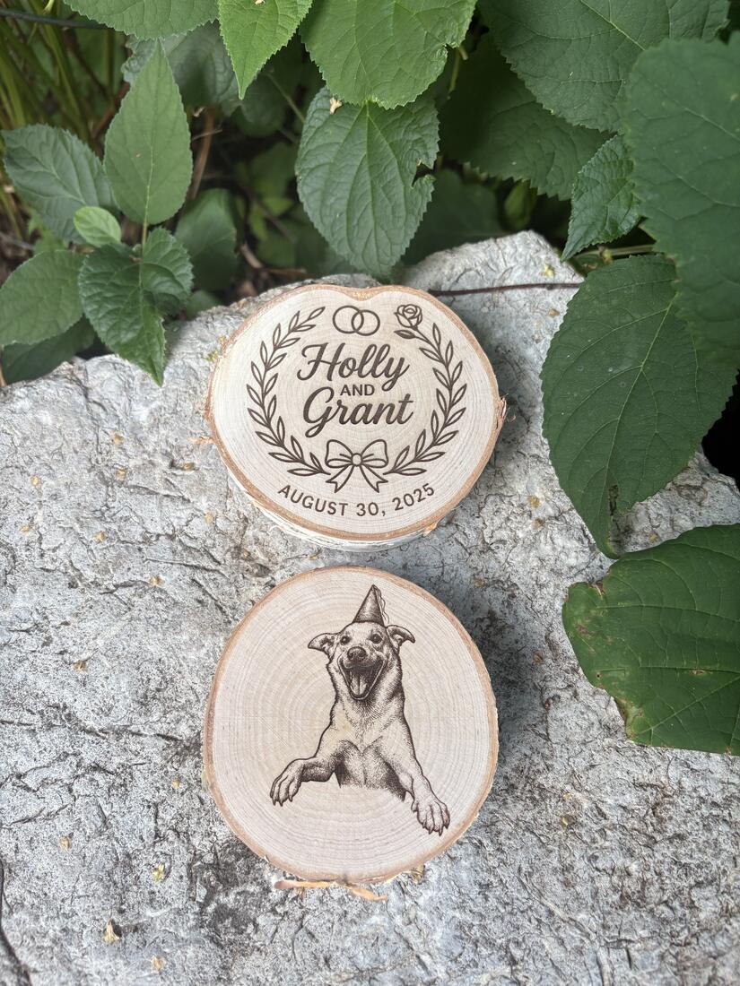 Two birch wood slices engraved with a wedding wreath reading Holly and Grant, August 30 2025, and a portrait of a dog in a party hat